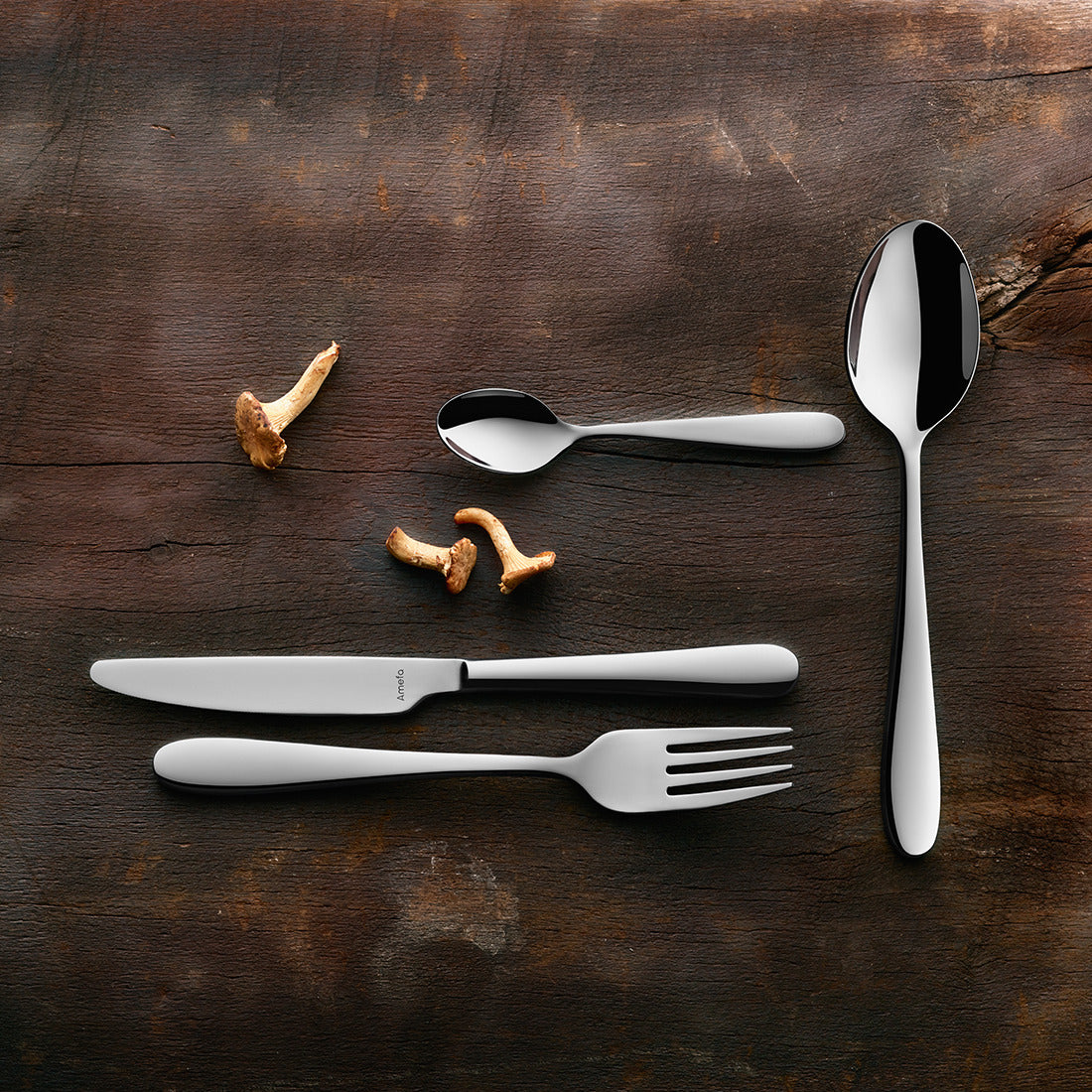 Besteckset und Pilze auf Holztisch.