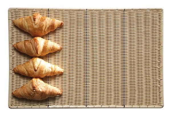 Vier Croissants auf geflochtener Unterlage.
