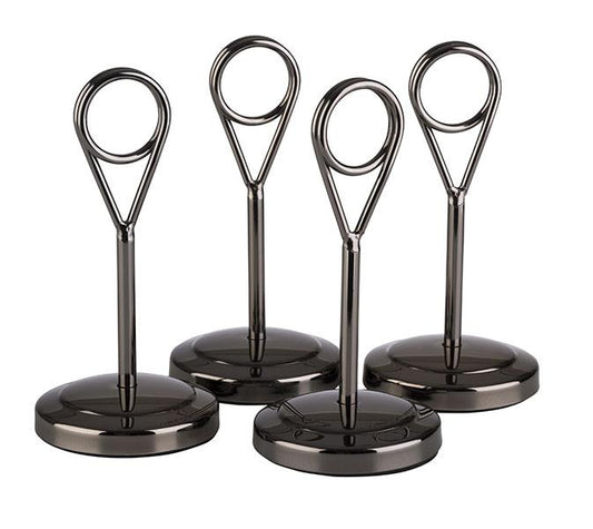 Vier silberne Tischkartenhalter stehen.