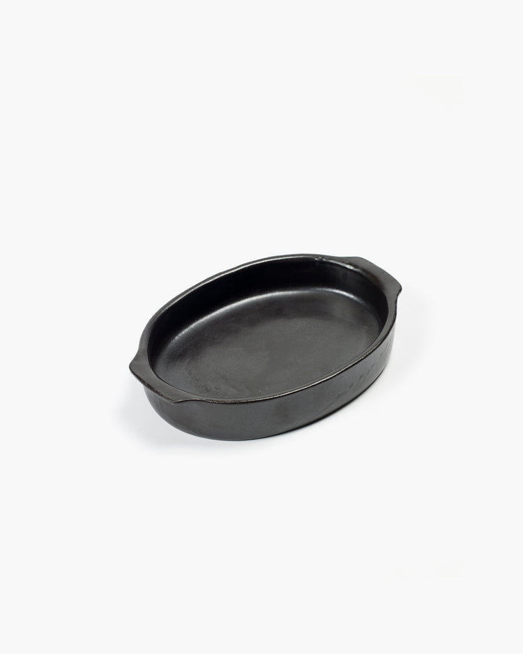 Schwarze ovale Auflaufform aus Gusseisen.