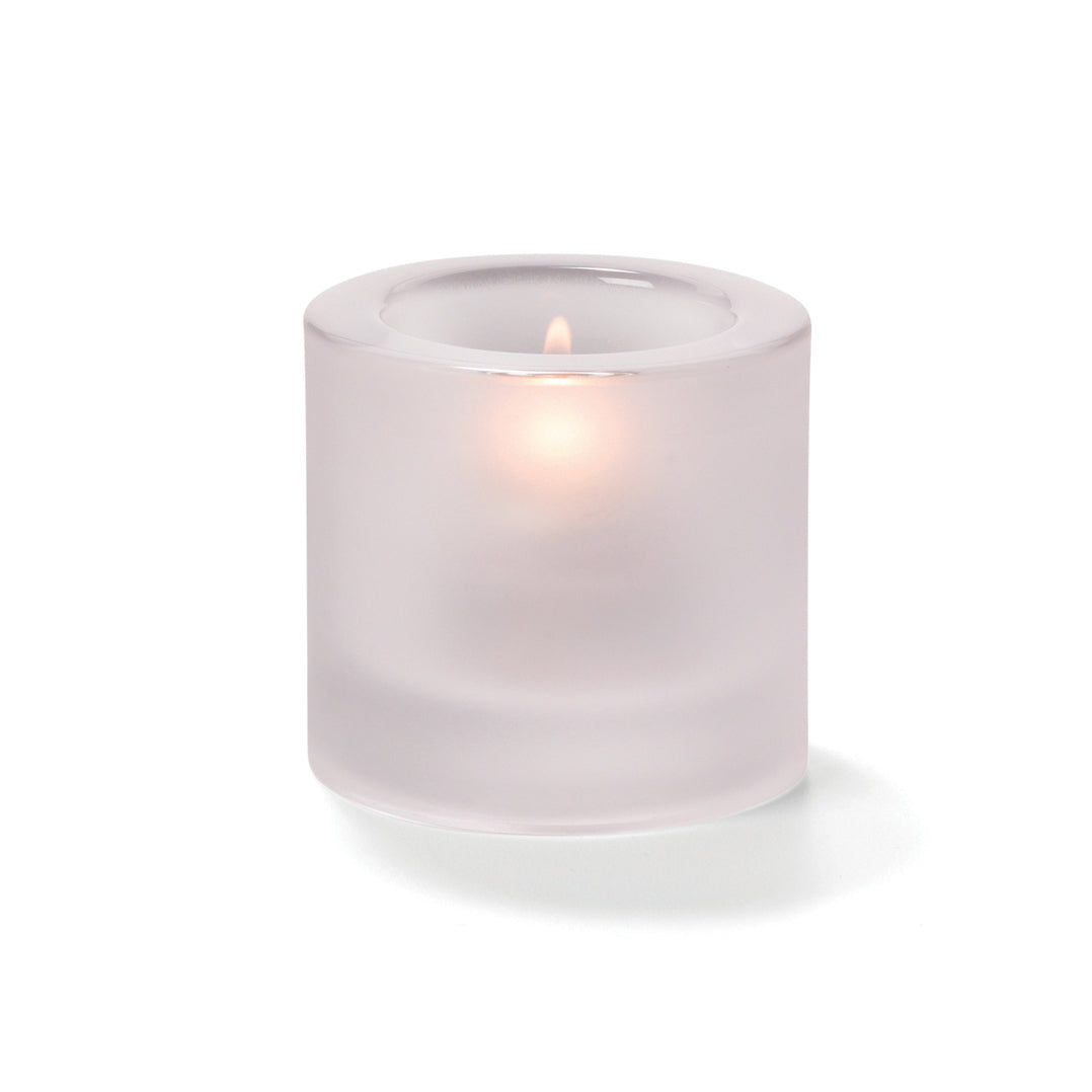 Kerze in mattem Glasbehälter.