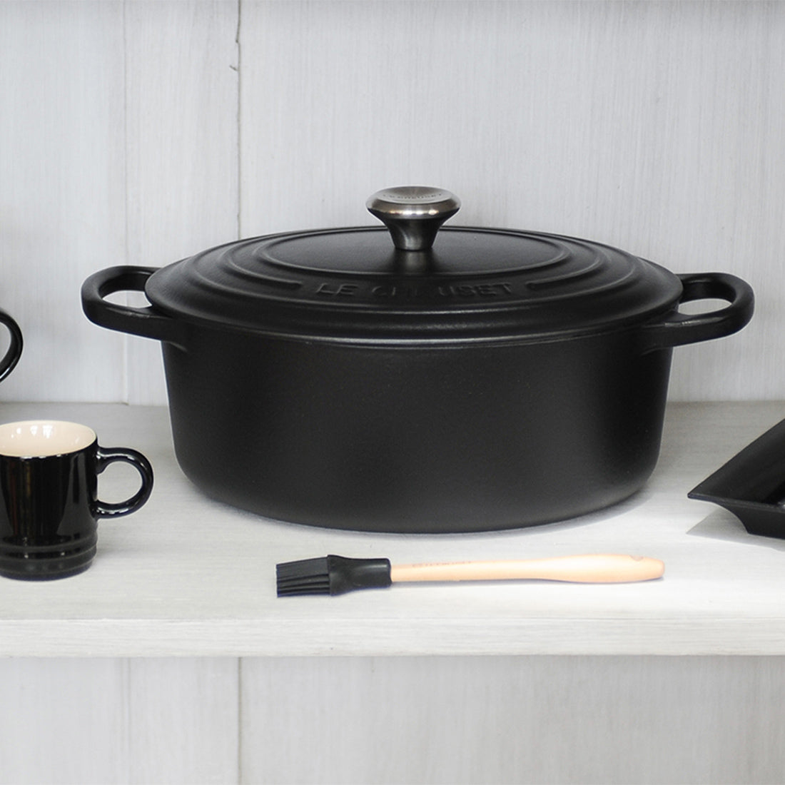 Schwarzer Bräter mit Tasse und Pinsel.