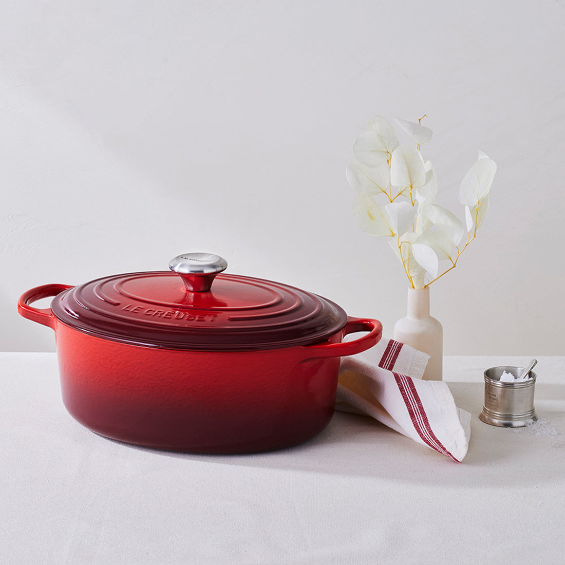 Roter Bräter, Vase, Serviette und Gewürzbehälter.