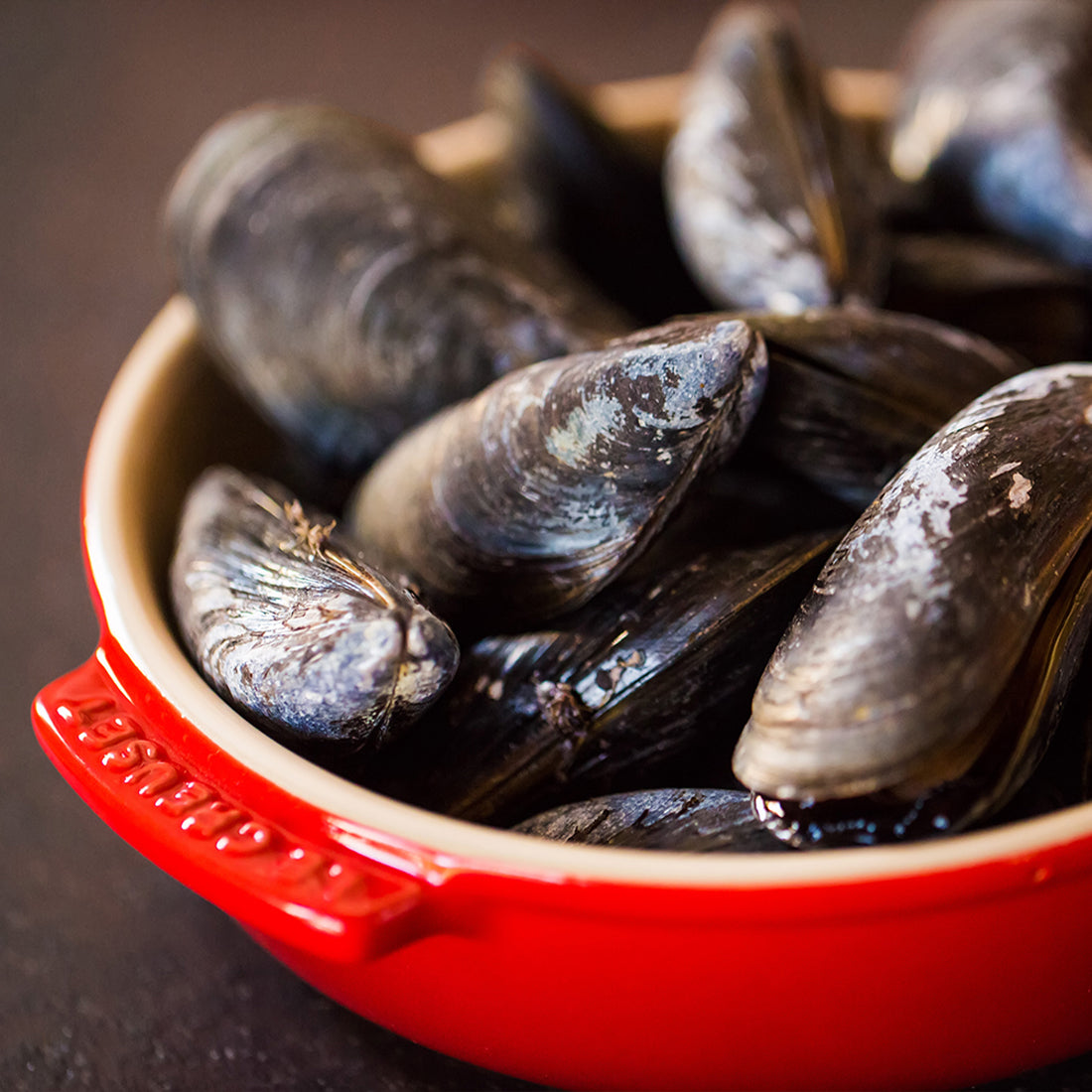 Rote Schüssel mit frischen Muscheln gefüllt.
