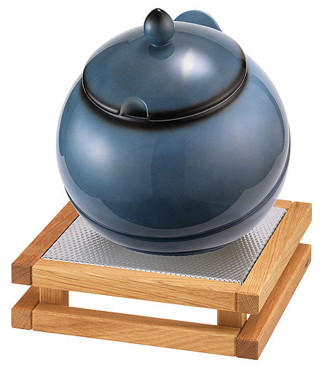 Blaue Teekanne auf Holzuntersetzer.