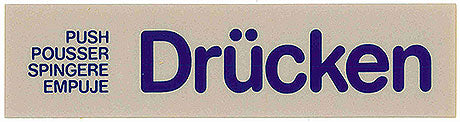 Türschild mit "Drücken" in mehreren Sprachen.
