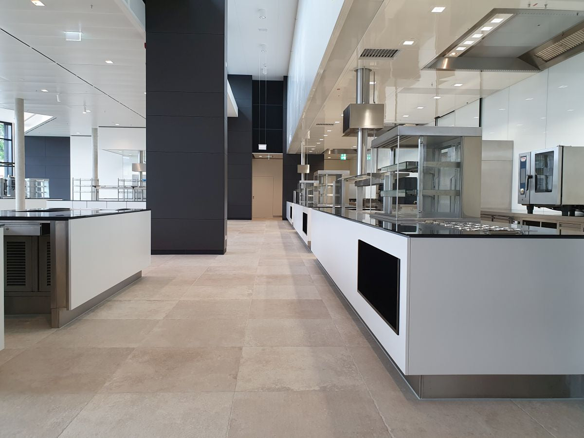 Moderne Großküche mit Edelstahlgeräten und Arbeitsflächen.