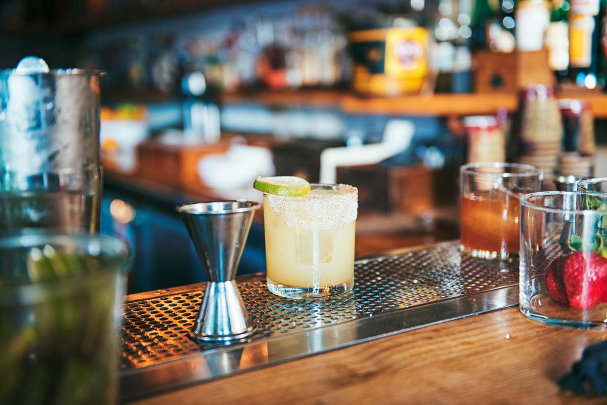 Cocktail auf Bartresen mit Limettenscheibe.