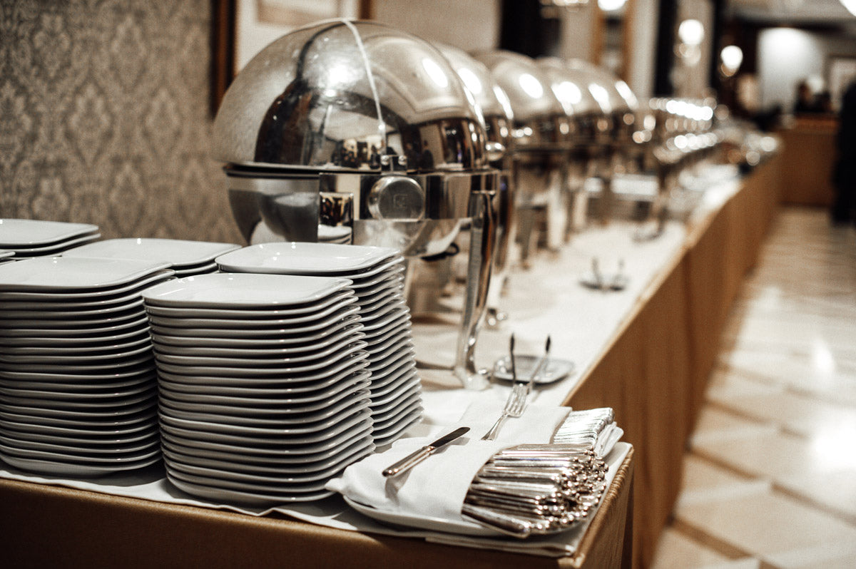 Buffet mit Tellern und Besteck in Reihe.