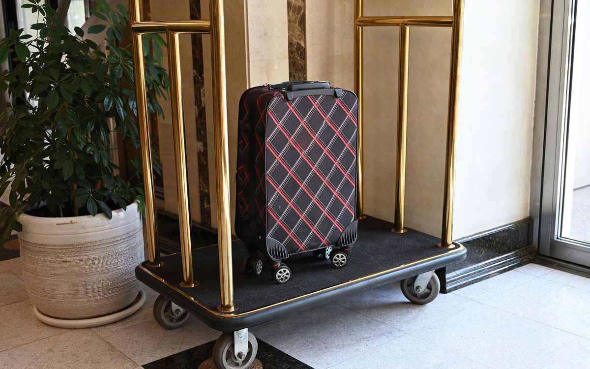 Gepäckwagen mit Koffer in Hotellobby.