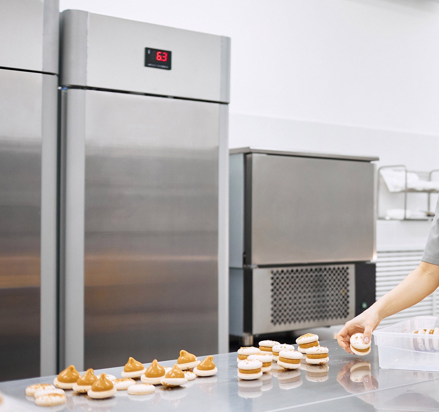 Küchengeräte und Macarons auf Edelstahloberfläche.