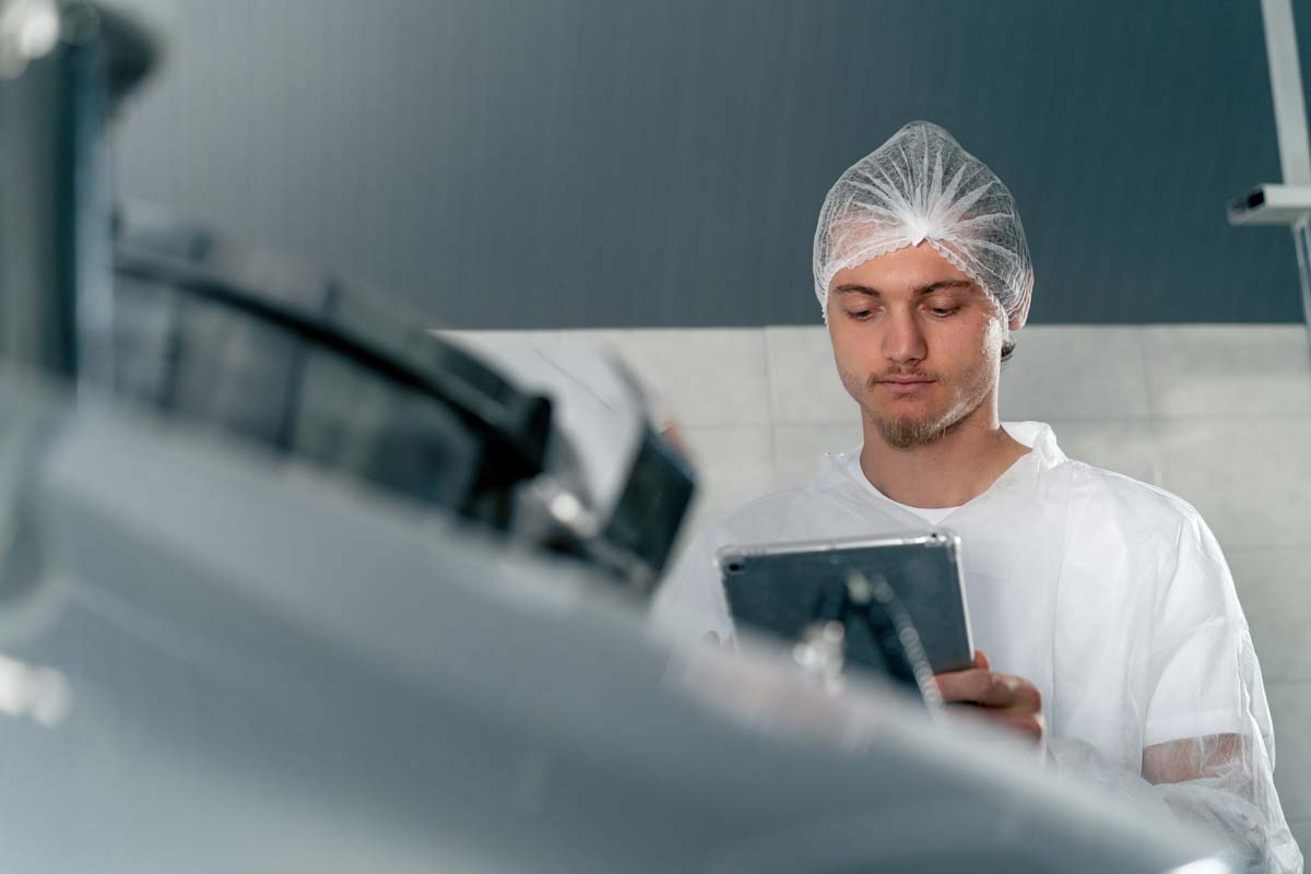 Mann in Schutzkleidung mit Tablet im Betrieb.