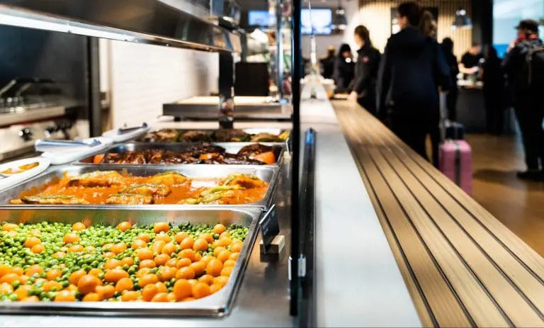 Kantine mit Buffet und Menschen im Hintergrund.