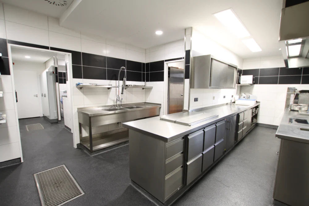 Moderne Großküche mit Edelstahloberflächen und Geräten.