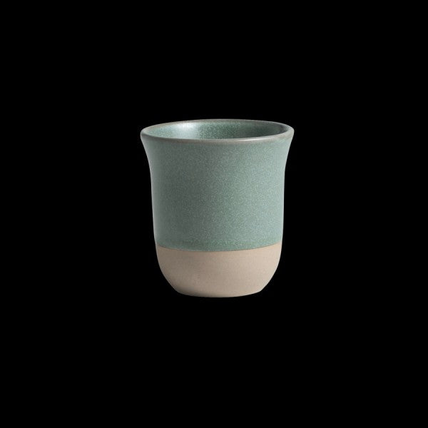 Grüner Keramikbecher auf schwarzem Hintergrund.