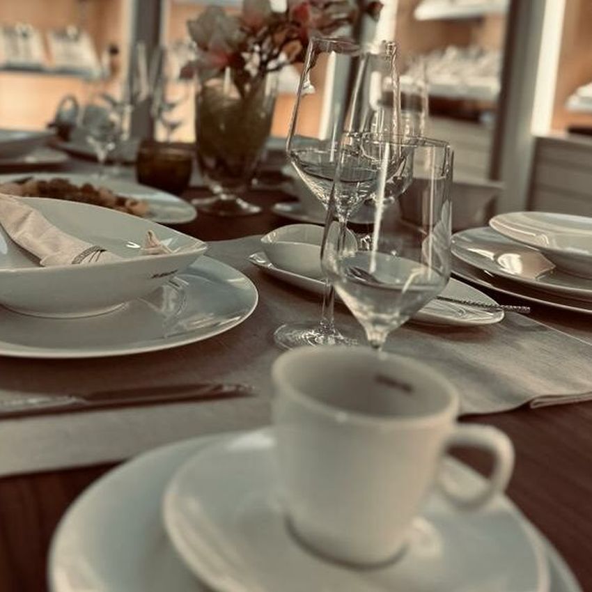 Gedeckter Tisch mit Geschirr und Gläsern.