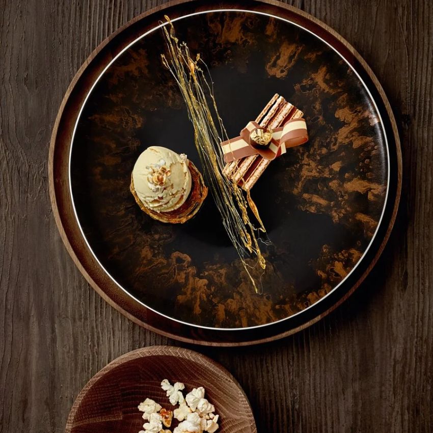Elegantes Dessert auf dunklem Teller angerichtet.